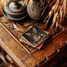 a wooden table topped with a book and vase filled with flowers