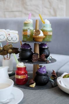 three tiered trays with cups and desserts on top of each other in front of a couch