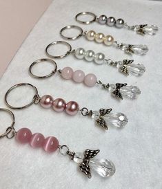 six pairs of key chains with beads and charms attached to them on a white surface