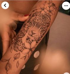 a woman's arm with a leopard and flowers tattoo on it