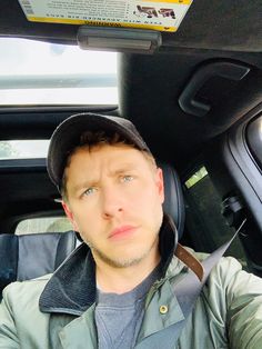 a man sitting in the back seat of a car wearing a black hat and jacket