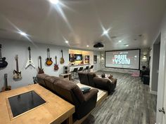 a living room with couches and guitars on the wall in front of a projector screen