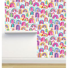 a white wall with colorful rainbows on it and a wooden floor in front of the wall