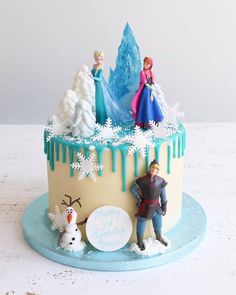 a frozen princess cake with two figures on top and frosting dripping down the sides