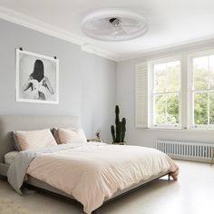 a bedroom with white walls and light colored furniture, including a bed that has pink sheets on it