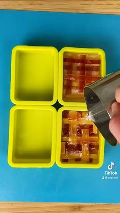 someone using a knife to cut pieces of ice cubes into four sections on a blue and yellow tray