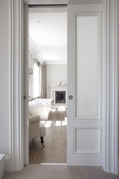 an open door leading to a living room with white walls and furniture in the background