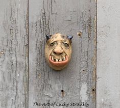 a mask mounted to the side of a wooden wall with words on it that read, the art of lucky stradley