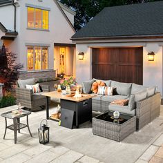 an outdoor living area with couches, tables and chairs in front of a house