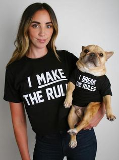 a woman holding a dog wearing a t - shirt that says i make the rules