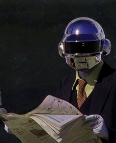 a man in a suit and helmet reading a newspaper