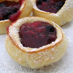 four pastries covered in powdered sugar and jelly