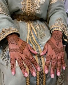 a woman's hands with henna tattoos on her arm and hand, all covered in gold chains