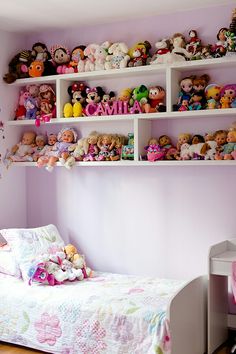 a child's bedroom with pink walls and shelves filled with stuffed animals on the wall