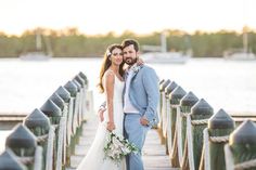 a bride and groom standing on a pier