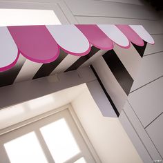 a pink and white awning hanging from the side of a window above a door