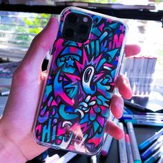 a person holding up a phone case with an artistic design on it