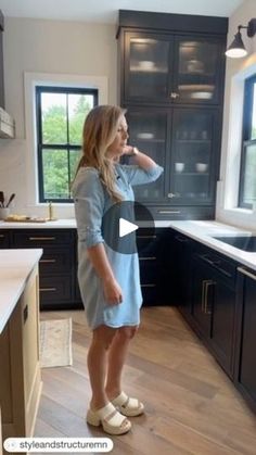 a woman standing in a kitchen next to a window