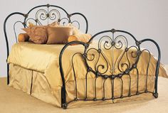 a metal bed with gold sheets and pillows