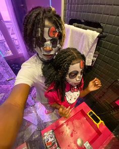 two children with face paint on their faces are standing in front of a mirror and looking at the camera