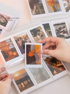 two hands are holding polaroid photos in front of several pictures on a table top