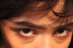 a close up of a person's face with long hair and eyeliners