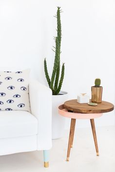 a white couch sitting next to a table with a potted cactus on top of it