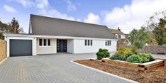 a white house with a driveway in front of it and landscaping around the entrance area