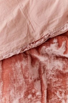 an unmade bed with pink and brown sheets on it's side, next to a pillow