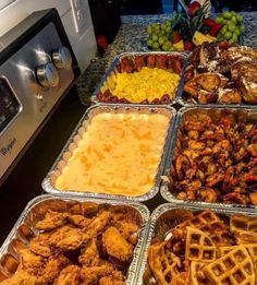 several trays of food sitting on top of a counter next to an oven and microwave