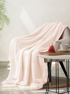 a blanket is draped over a table with a bowl of fruit and cup on it