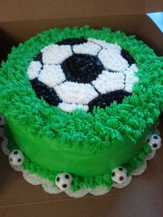 a green cake with white and black frosting in a box on top of a table