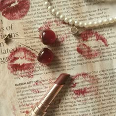 lipstick and pearls are laying on an old book