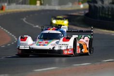 a race car driving on a track with other cars behind it