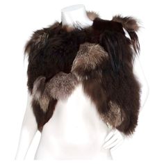 The Yves Saint Laurent Avant Garde Multi-Fur Patch Vest from the 1980s is a stunning statement piece that celebrates the artistry and extravagance of vintage fashion. Crafted from an exquisite blend of various furs, including goat, lamb, and fox, this vest showcases a harmonious mix of rich brown shades, creating a unique texture and depth. Its cropped silhouette is both flattering and versatile, with a hook closure option at the top that allows for your preferred styling. This rare gem pairs ef Patch Vest, Azzedine Alaïa, Chanel Skirt, Purple Blazer, Azzedine Alaia, Cape Jacket, Alley Cat, Black Tweed, Cropped Vest