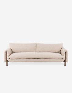 a beige couch with wooden legs on a white background