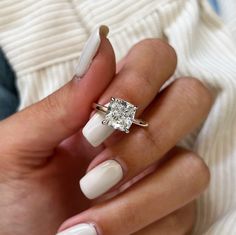 a woman's hand with white manicured nails and a diamond ring