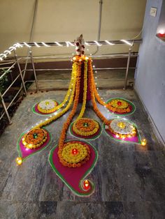 an arrangement of flowers and candles on the ground in front of a staircase with railings