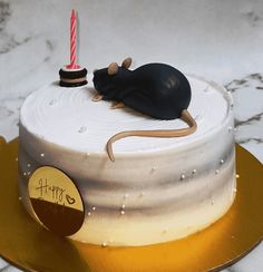 a birthday cake with a rat on top and a candle in the shape of a mouse