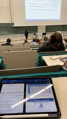 a classroom full of students with laptops and papers on the desk in front of them