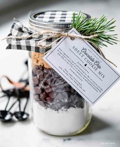 a mason jar filled with black and white candies next to a christmas ornament