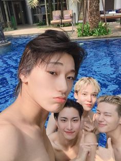 four people are posing in front of a swimming pool