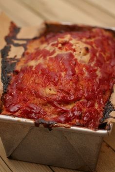 a square pizza in a metal pan on a wooden table