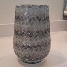 a glass vase sitting on top of a white counter next to a framed photo in the background