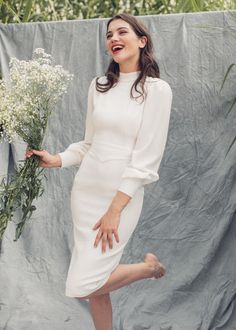 a woman in a white dress is smiling and holding a bunch of baby's breath flowers