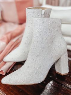 a pair of white boots sitting on top of a wooden floor