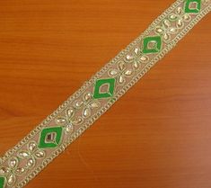 a green and white beaded belt on a wooden surface