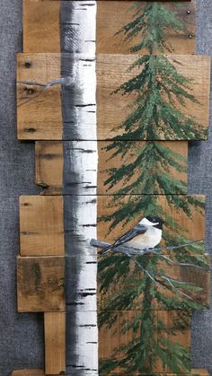 a bird sitting on top of a tree next to a wooden sign with trees painted on it