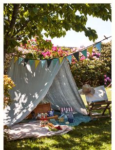 an outdoor picnic setting under a tree with flowers on the branches and clothes hanging over it