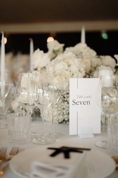 the table is set with white flowers and wine glasses for an elegant wedding reception or special event